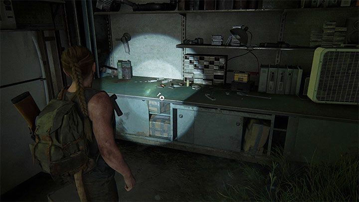 Zu Fuß Im Hangar befindet sich eine Werkbank, in der sich ein hängendes Boot befindet. - The Last of Us 2: Upgrades für Werkbänke und Waffen - Charakterentwicklung und Ausrüstungs-Upgrades - The Last of Us 2 Guide